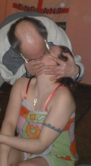 Gordon Cragg with head bowed showing his bold crown smogs Phennel as she sits at the edge of the stage with reb bra straps showing above the towel she is wrapped in.